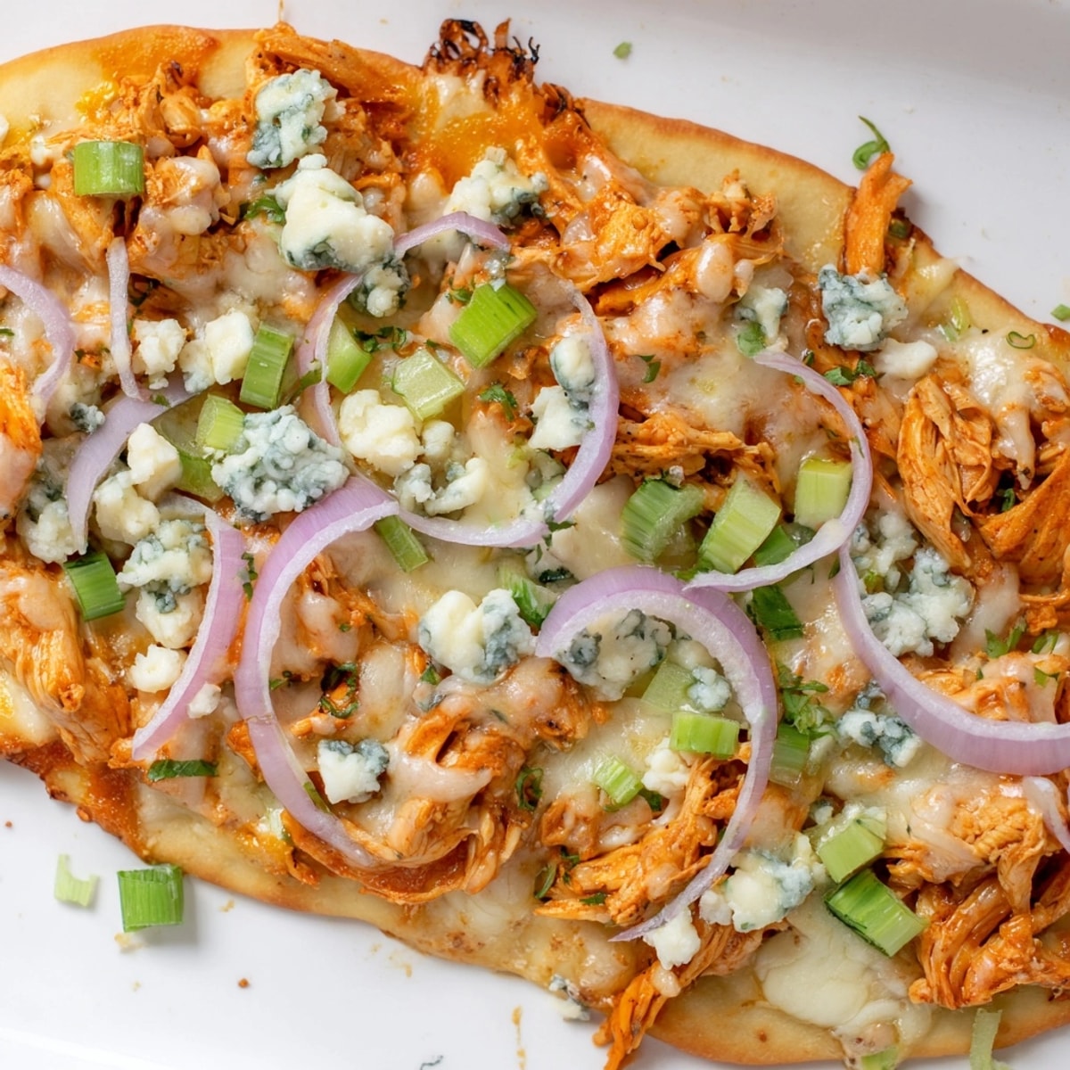 A tempting slice of Buffalo Chicken and Blue Cheese Flatbread displaying tangy flavors, perfect meal.