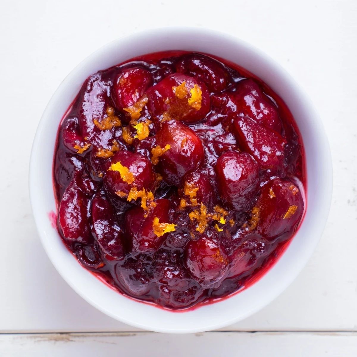 A glistening bowl of homemade Cranberry Compote, bursting with vibrant red berries.