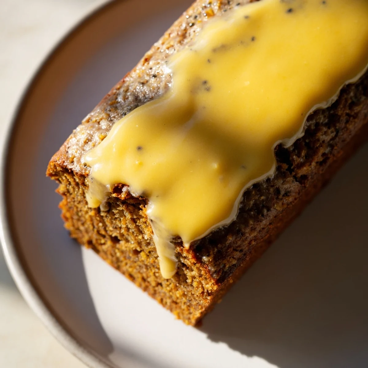 A slice of gingerbread loaf with lemon glaze, offering comforting spiced flavors and tangy icing.