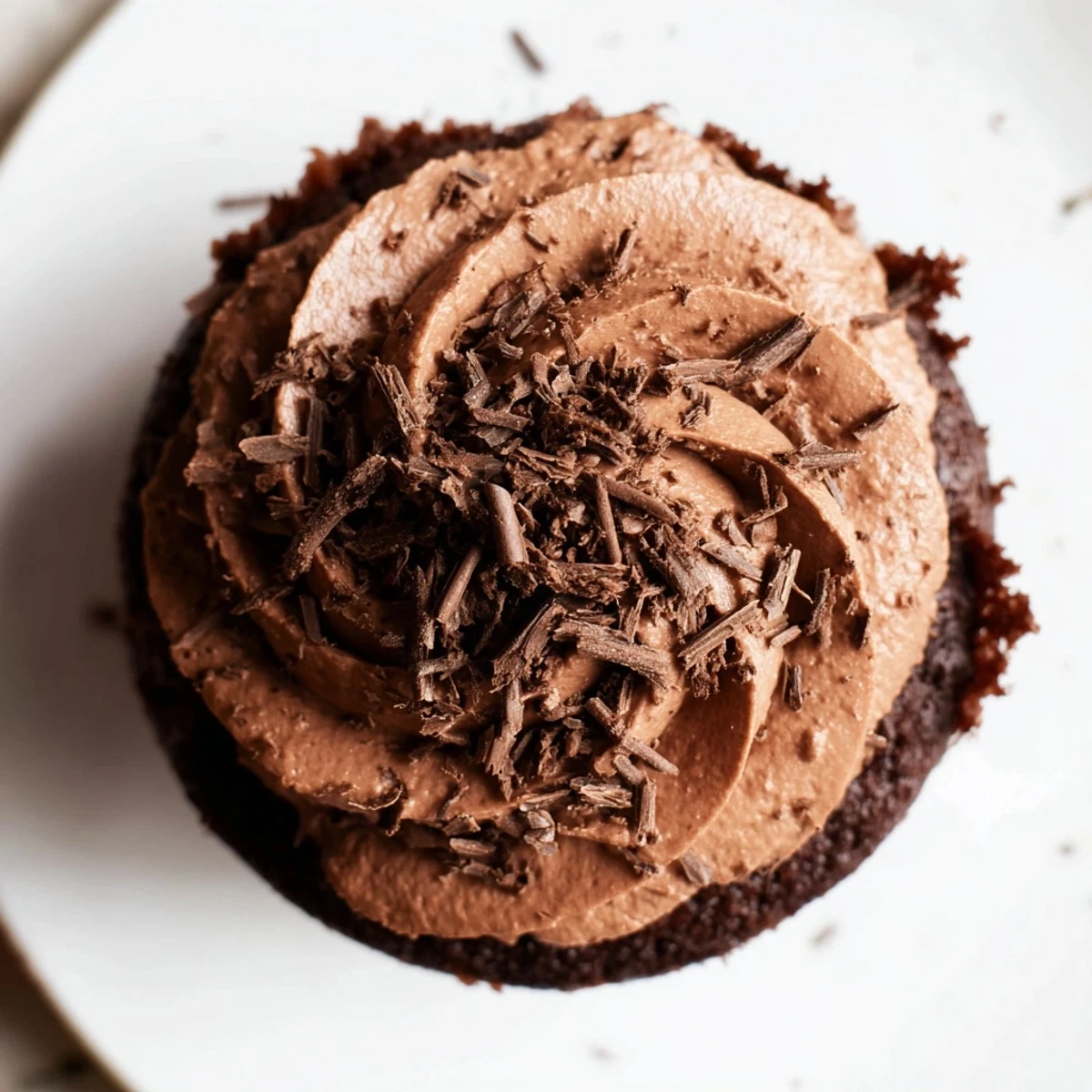 Moist chocolate cupcake, frosted, with a dusting of cocoa, ready for a delicious dessert.