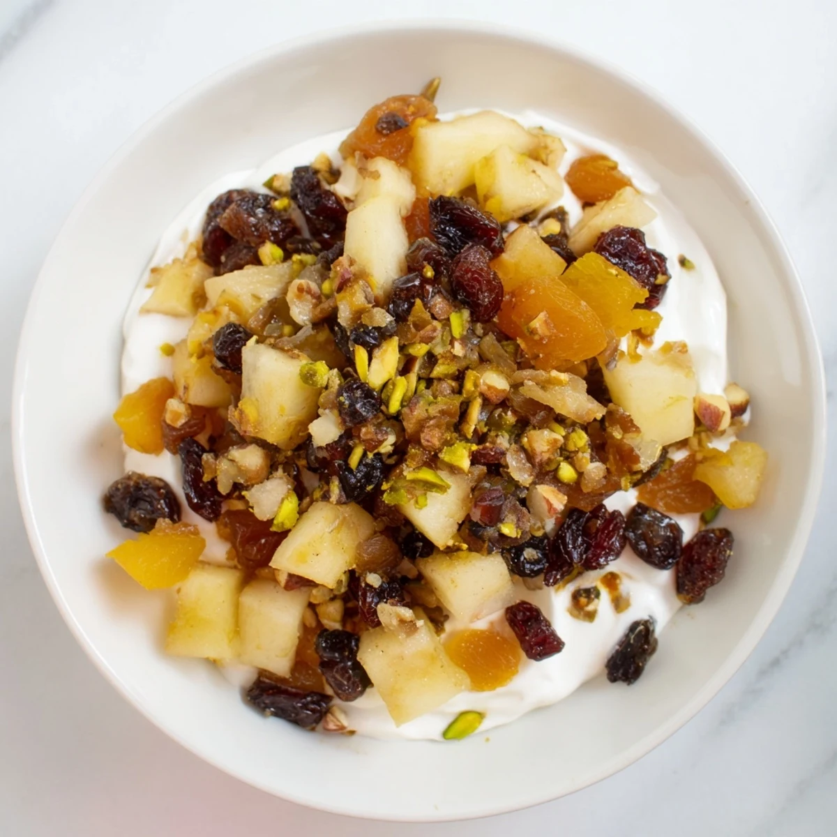 Golden, syrupy winter fruit compote with vibrant apples and pears ladled over thick, white yogurt.