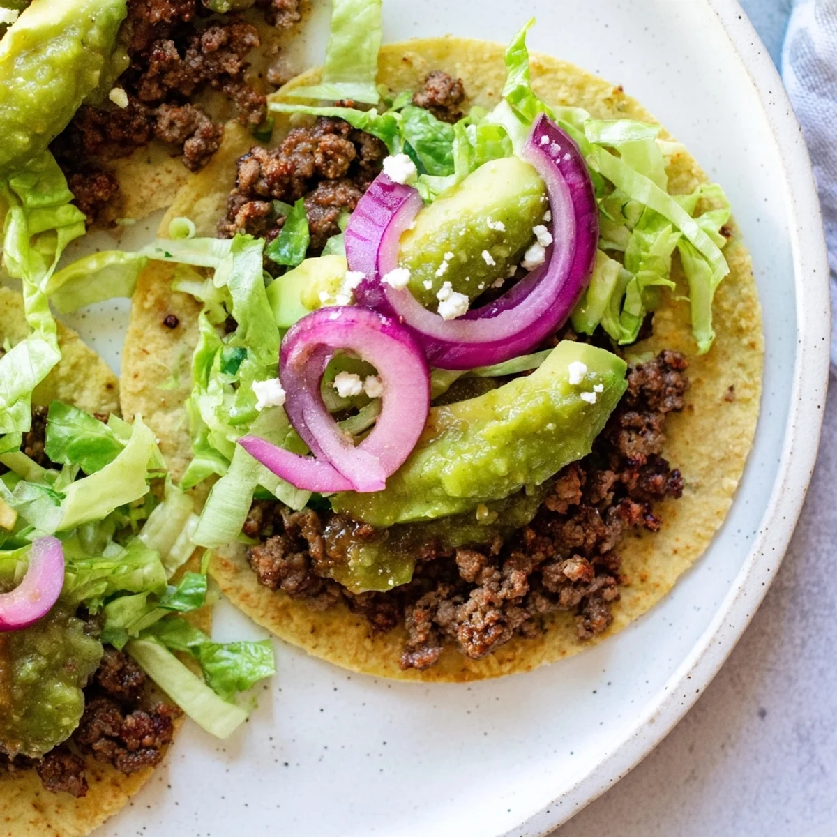 Close-up of fully-loaded beef tacos, showcasing the spiced beef and fresh salsa verde's delicious flavors.