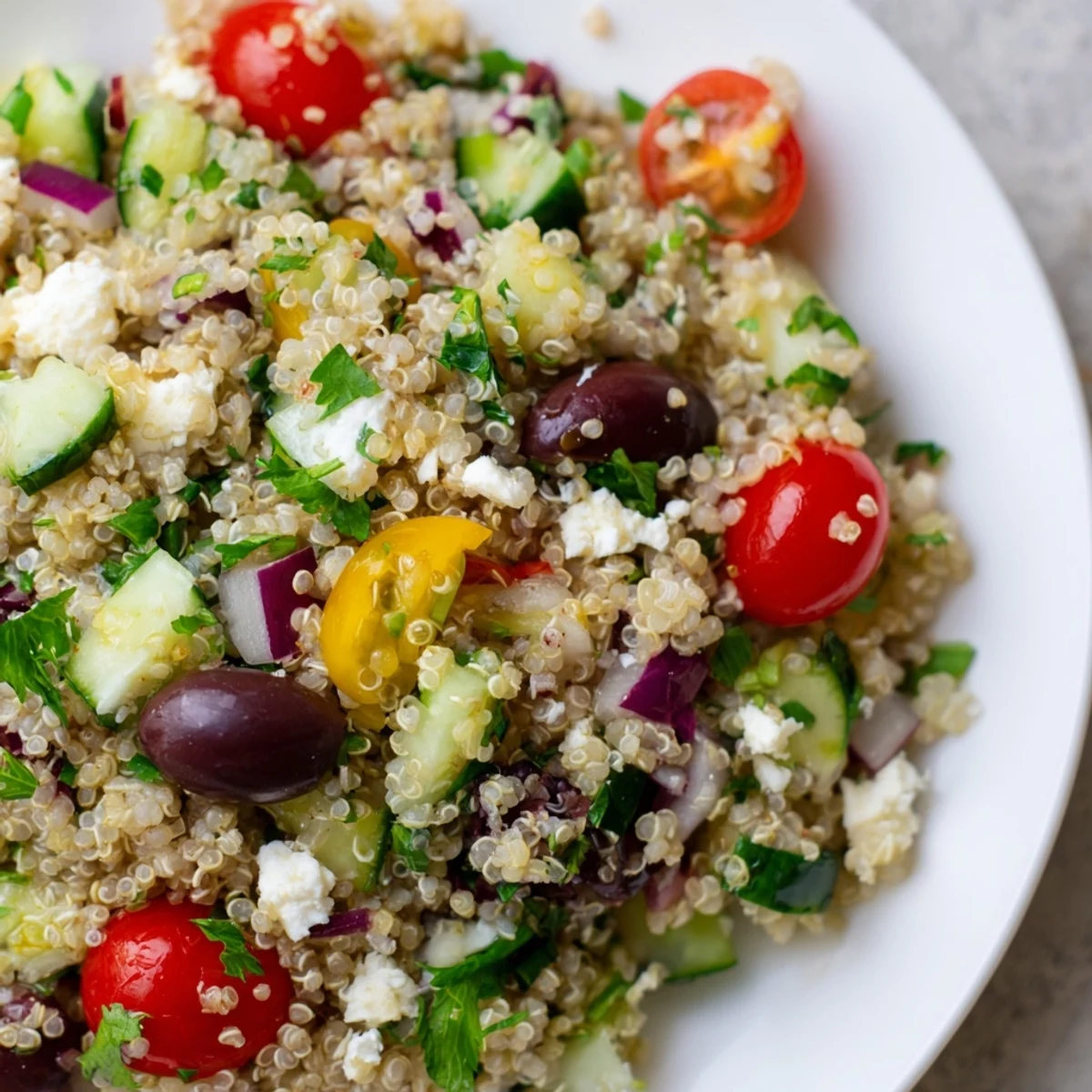 Close-up of a refreshing Mediterranean Quinoa Salad, showcasing bright cherry tomatoes and feta cheese crumbles.