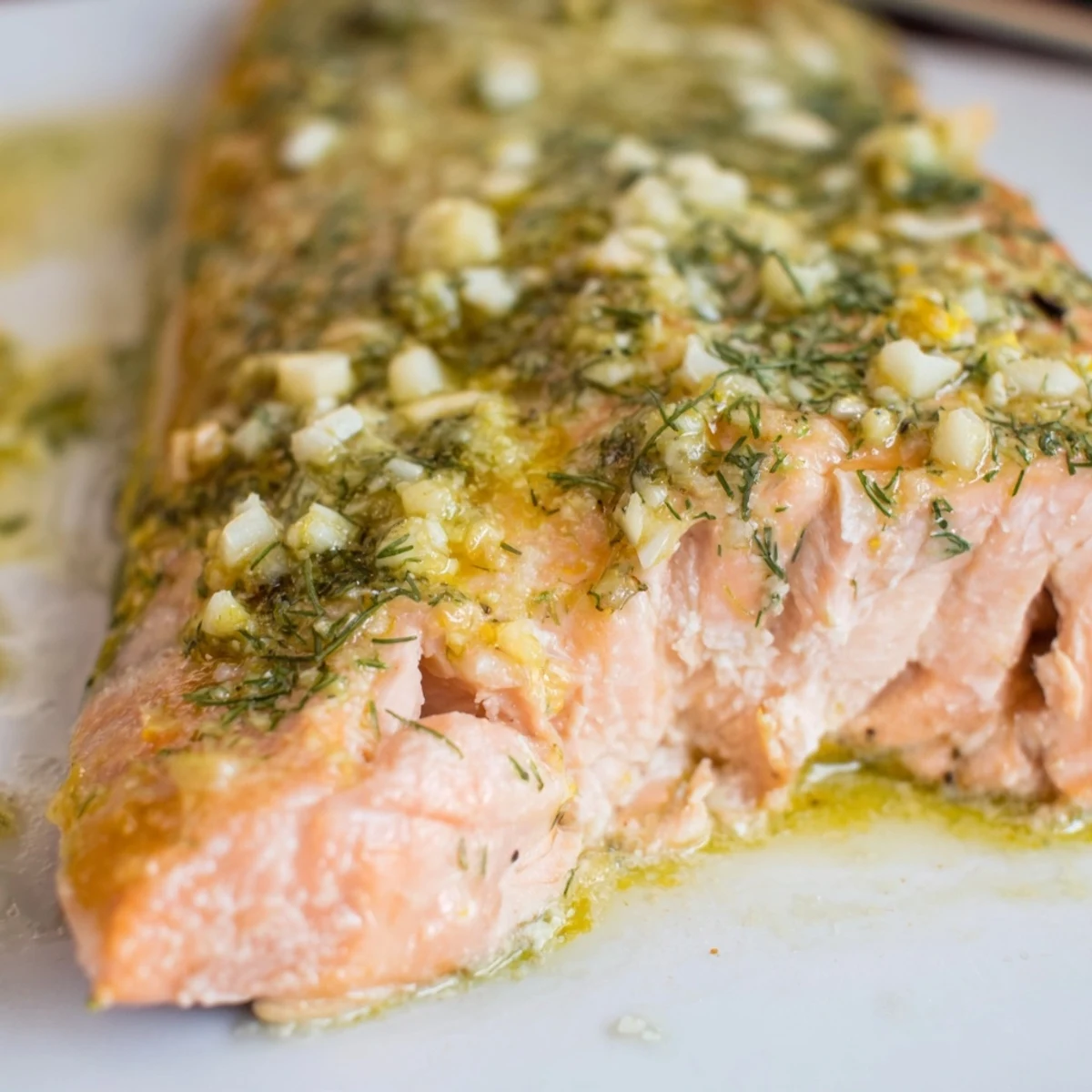 Golden Baked Salmon with Dill and Lemon Butter Sauce fillets topped with bright green herbs and lemon slices.