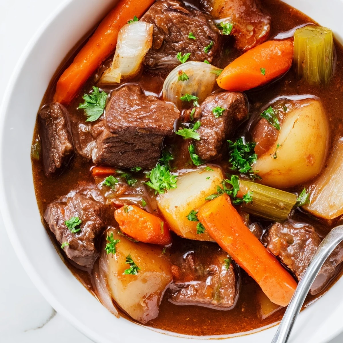 Bowl of slow cooker beef stew with carrots and potatoes, served steaming hot with fresh parsley garnish.