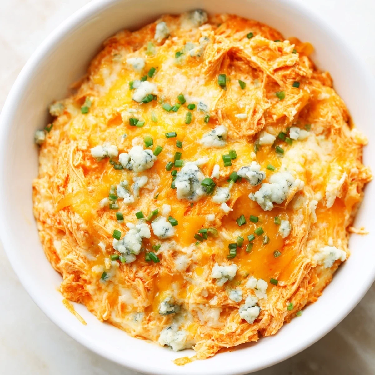 Golden brown Spicy Buffalo Chicken Dip bubbling in a ceramic dish, surrounded by crisp celery sticks for dipping.