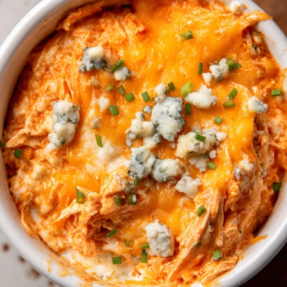 Spicy Buffalo Chicken Dip baked to golden perfection in a dish, ready to serve with crunchy celery sticks.