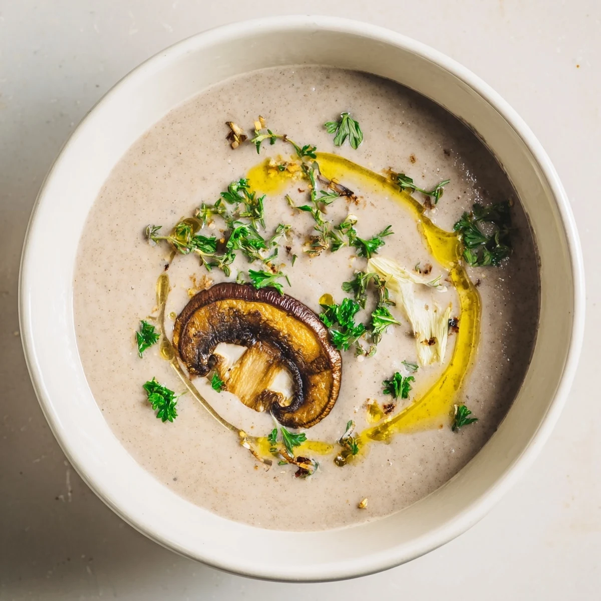 A close-up of Creamy Mushroom Soup with Thyme, featuring golden sautéed mushrooms and a rich, creamy broth with fresh thyme sprigs.