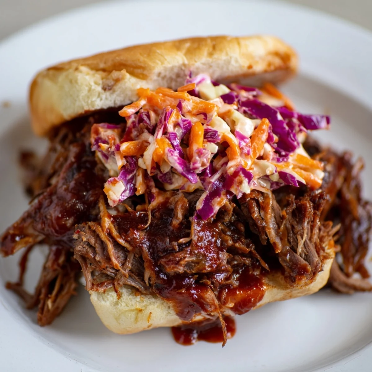 Fork-tender Slow Cooker Pulled Beef Sandwiches with zesty coleslaw piled high on a toasted bun.