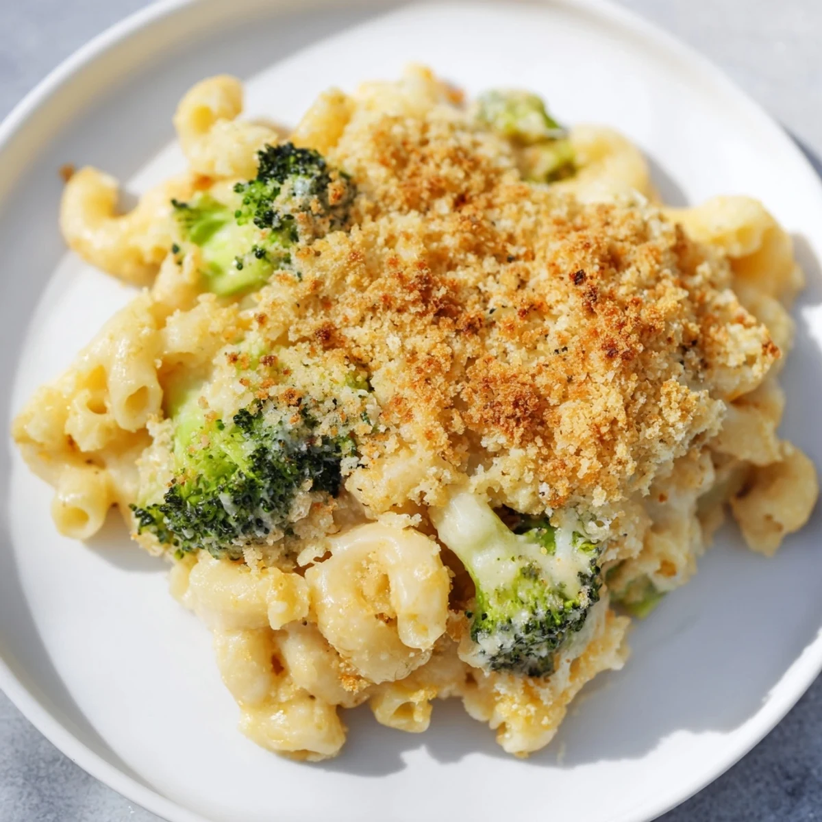 A close-up of homemade baked macaroni and cheese with broccoli, showcasing a creamy cheddar sauce and a golden panko crust.
