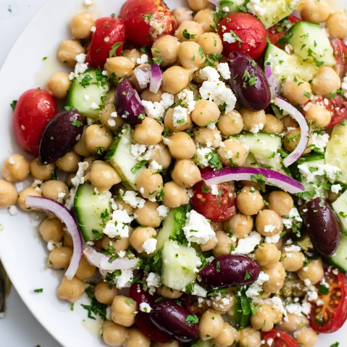 Mediterranean Chickpea Salad with Feta in a white bowl, colorful vegetables and chickpeas tossed with a zesty lemon-olive oil dressing.