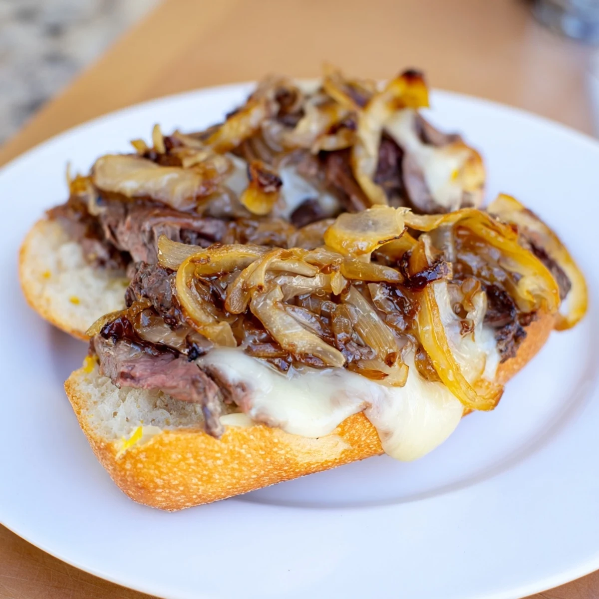 Toasted baguette holds juicy ribeye steak slices, sweet caramelized onions, and melted provolone cheese in this MVP Steak Sandwiches recipe.