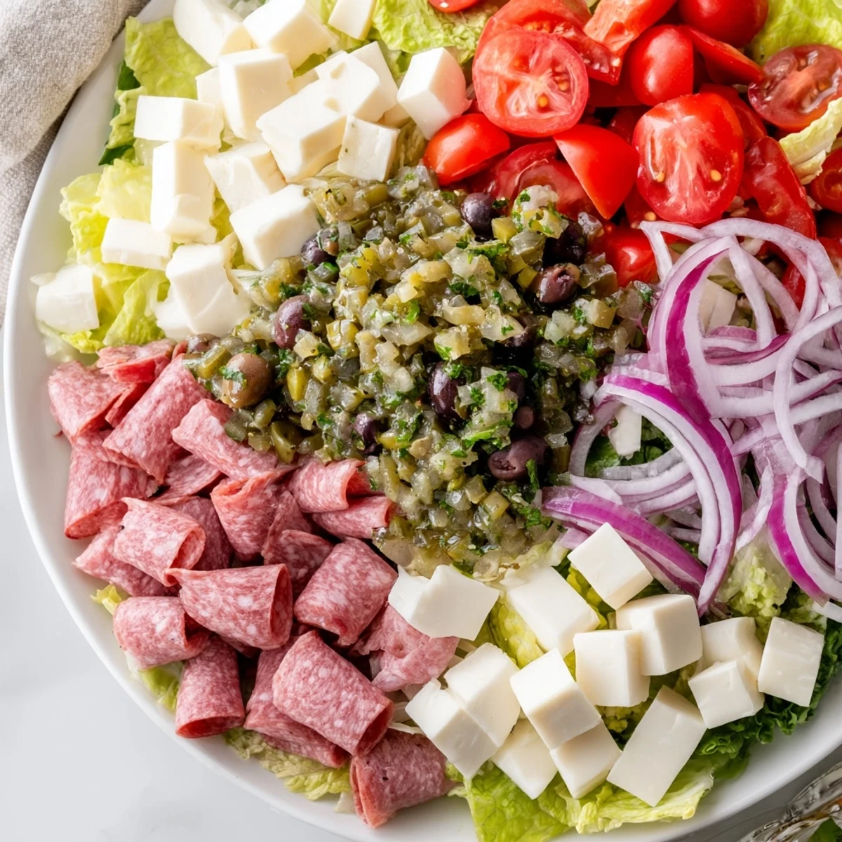 Freshly tossed New Orleans Muffuletta Salad features salami, provolone, and olive relish on crisp romaine. Hearty and vibrant.