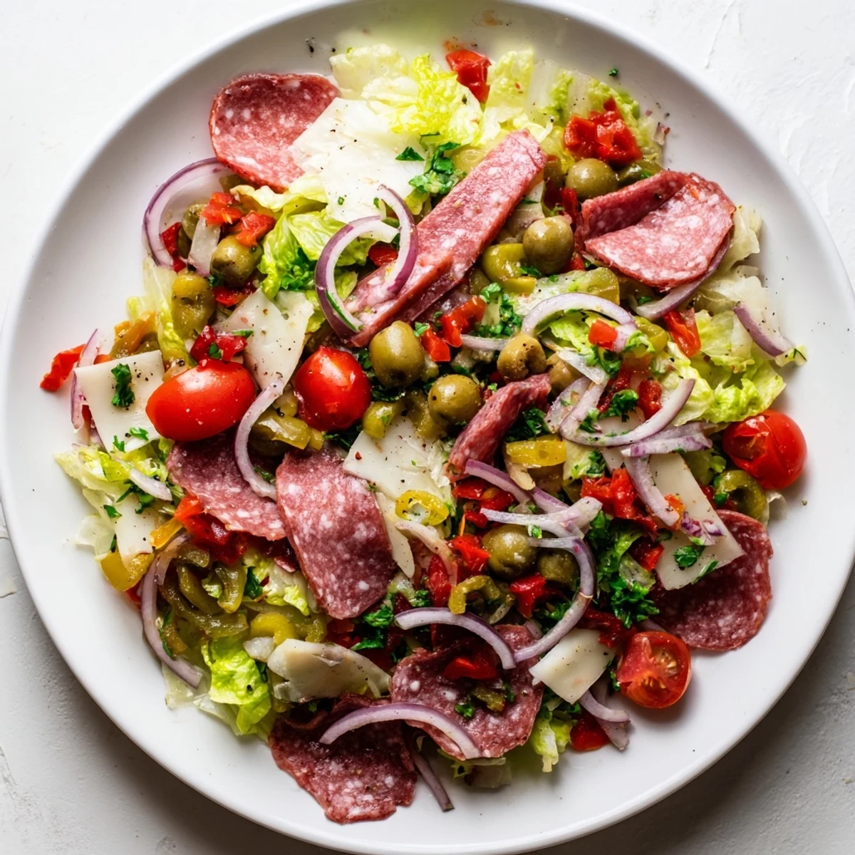 A vibrant New Orleans Muffuletta Salad showcases chopped romaine with cured meats, provolone, and tangy olive salad.