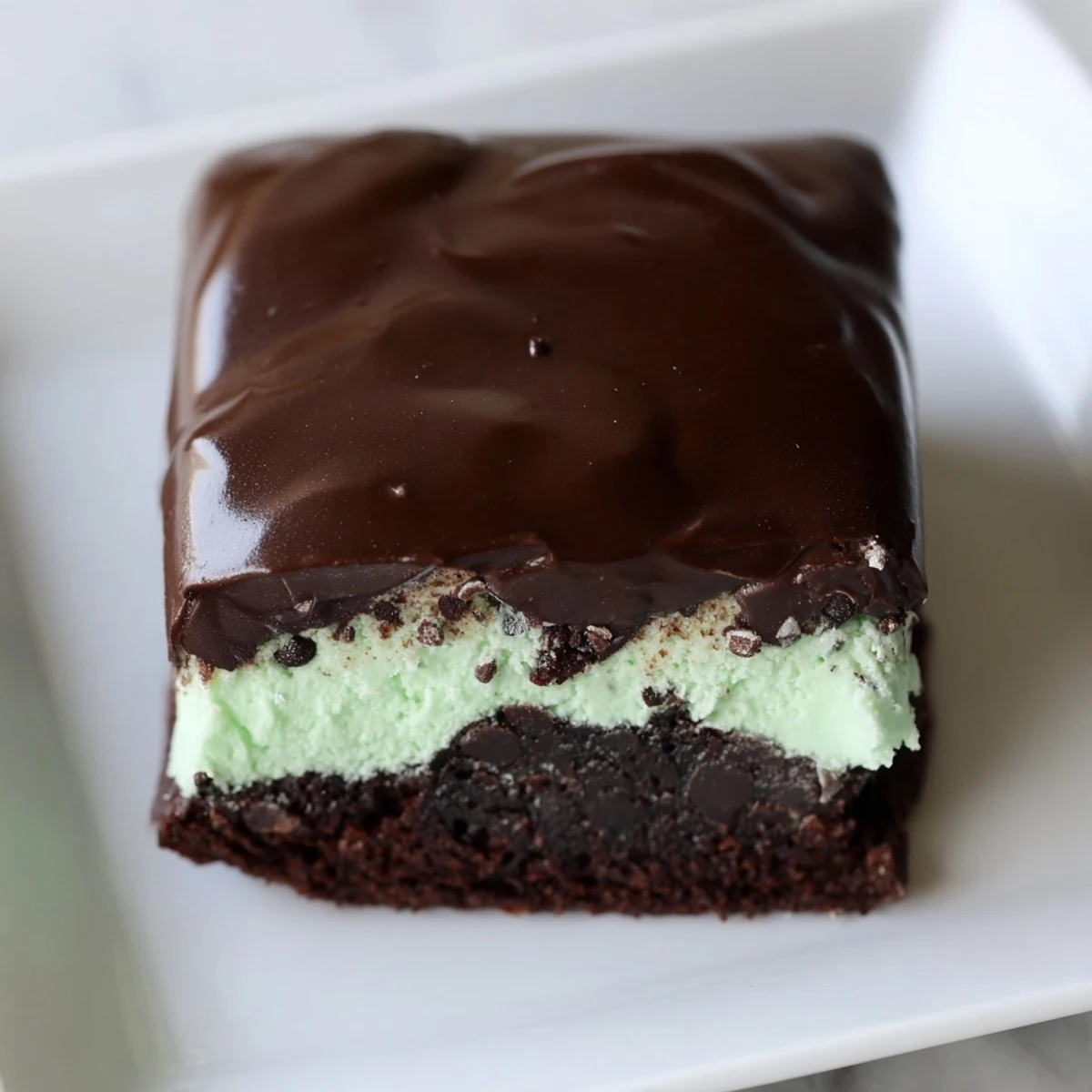 Fudgy Mint Chocolate Chip Brownies with Ganache topped with glossy chocolate and mint chunks.