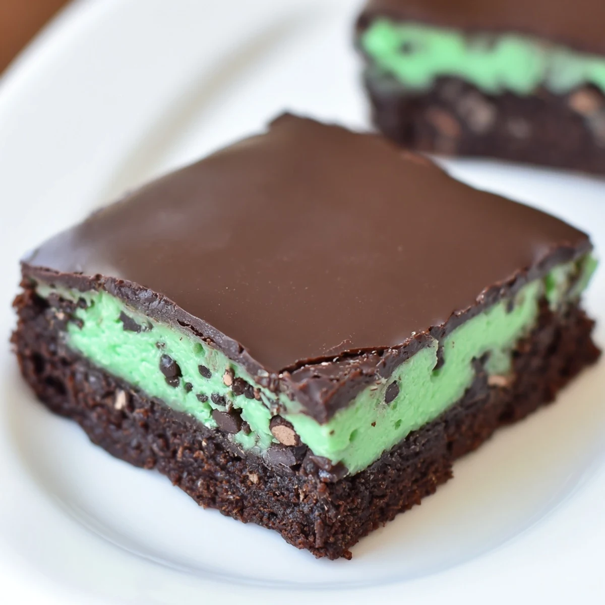 Warm Mint Chocolate Chip Brownies served with a glass of cold milk, highlighting the rich chocolate and refreshing mint layers in an inviting scene.