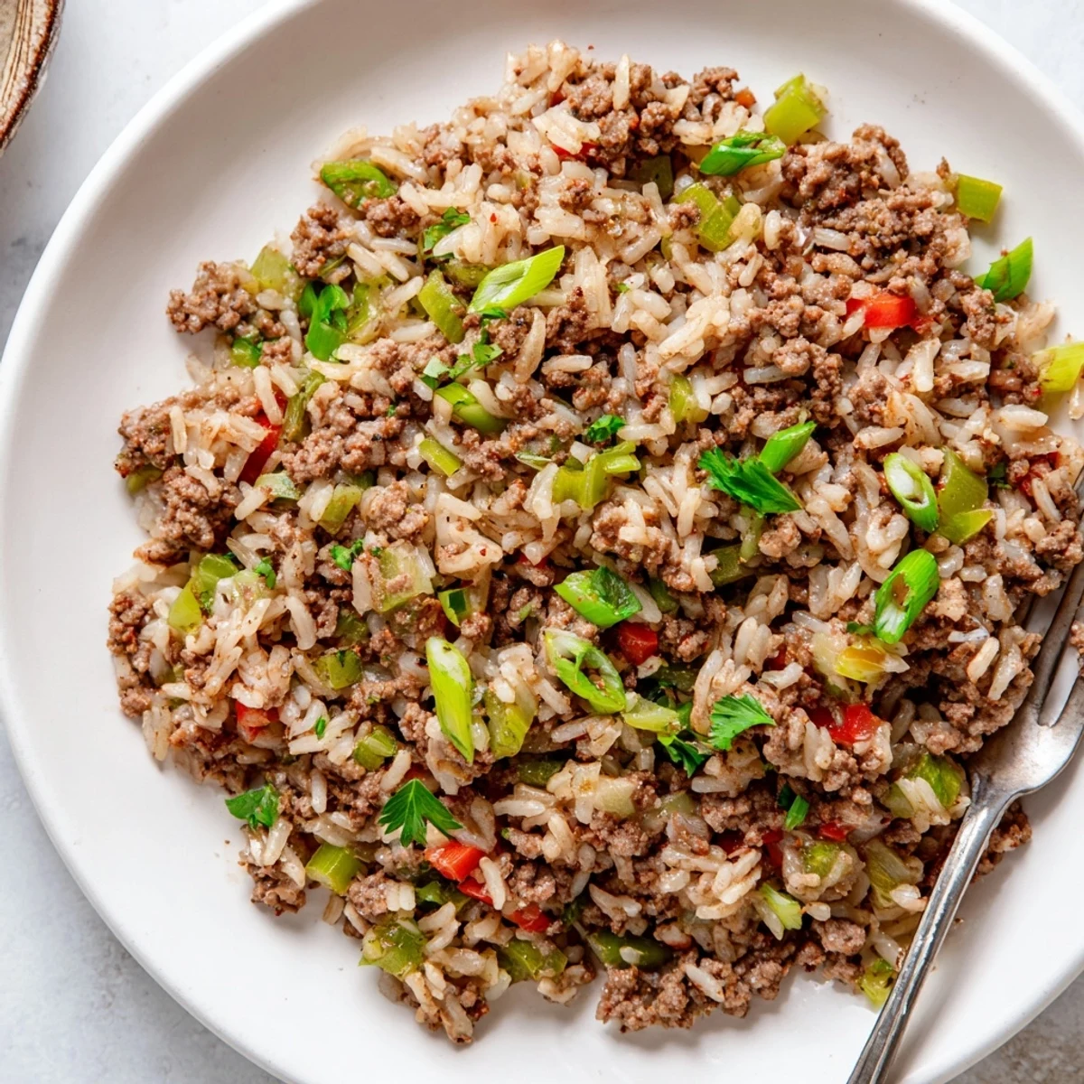 Cajun Dirty Rice with Ground Beef served in a rustic white bowl, featuring tender grains mixed with savory ground beef and veggies.