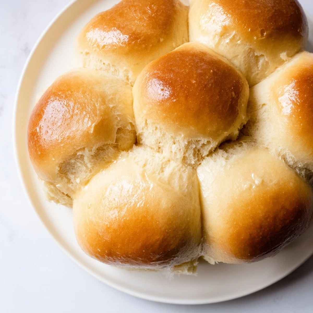 Freshly baked Best Vegan Dinner Rolls golden brown and brushed with melted vegan butter in a baking dish.
