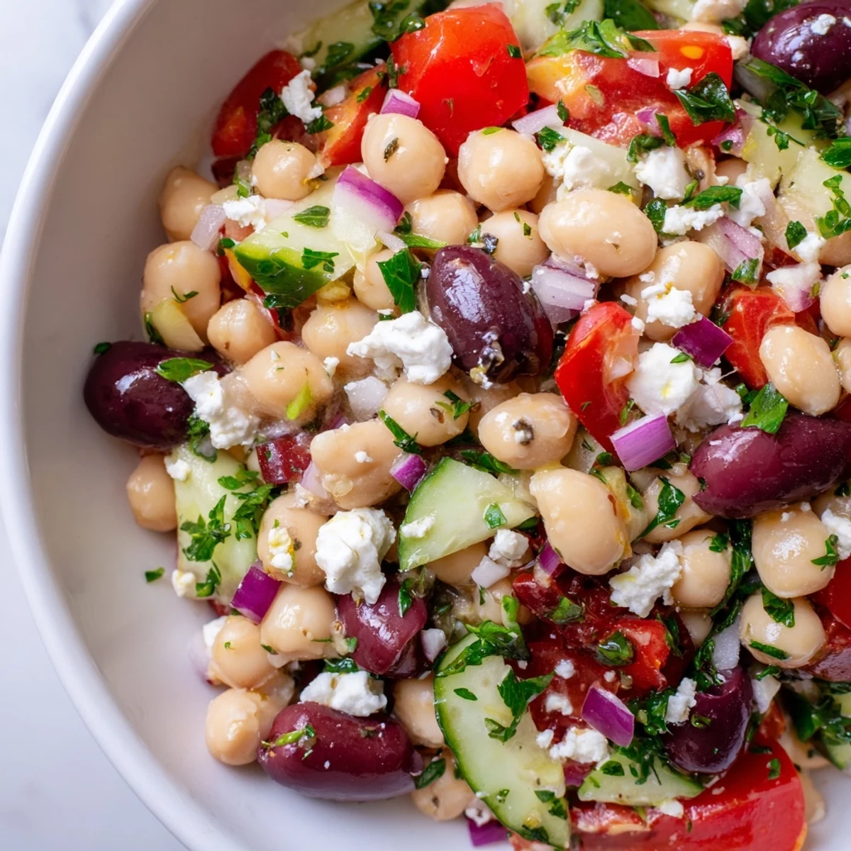 A close-up of the Mediterranean Dense Bean Salad showing colorful chickpeas, kidney beans, and fresh cherry tomatoes.