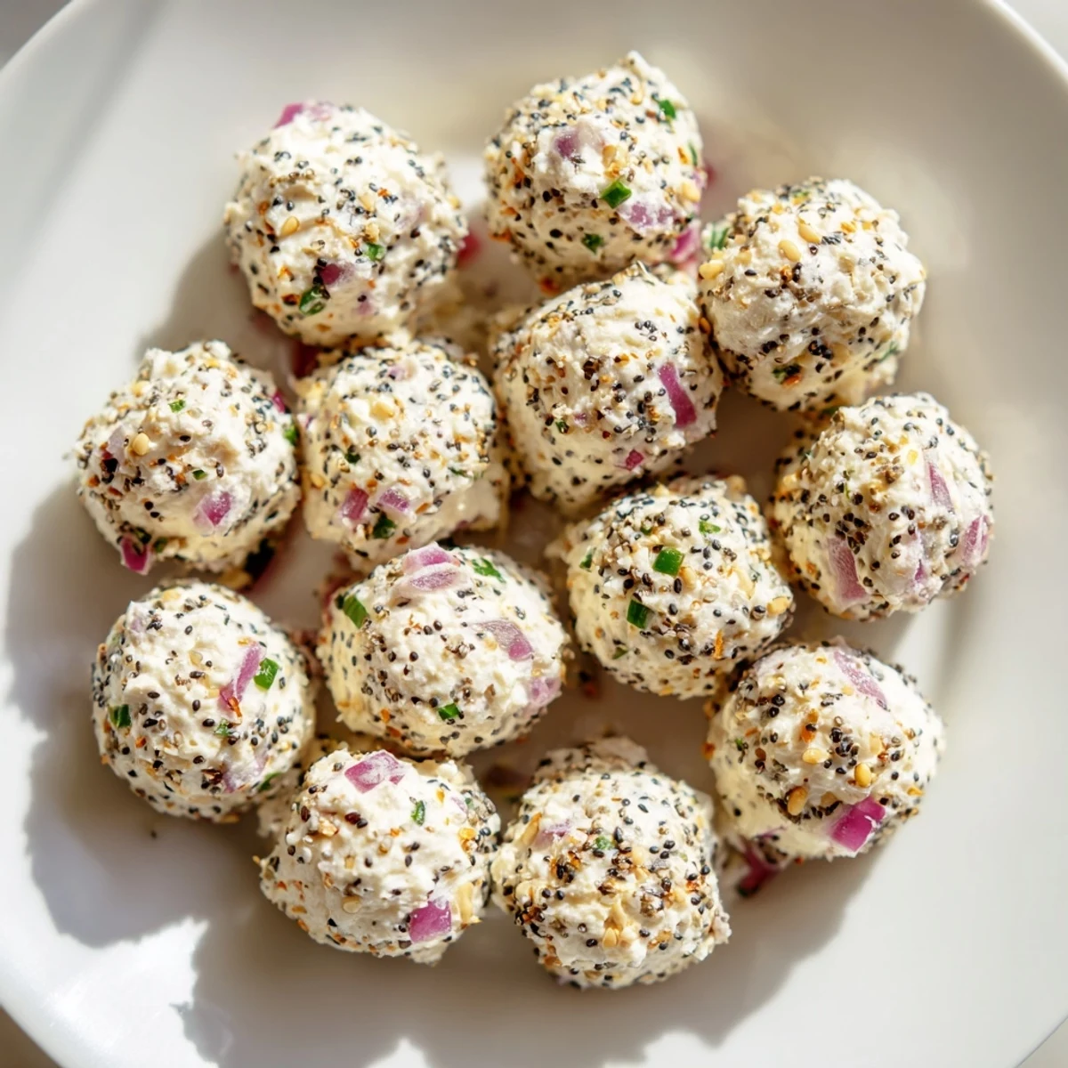 Bright white Everything Bagel Cottage Cheese Bites sit on a platter, coated with sesame seeds and poppy seeds.