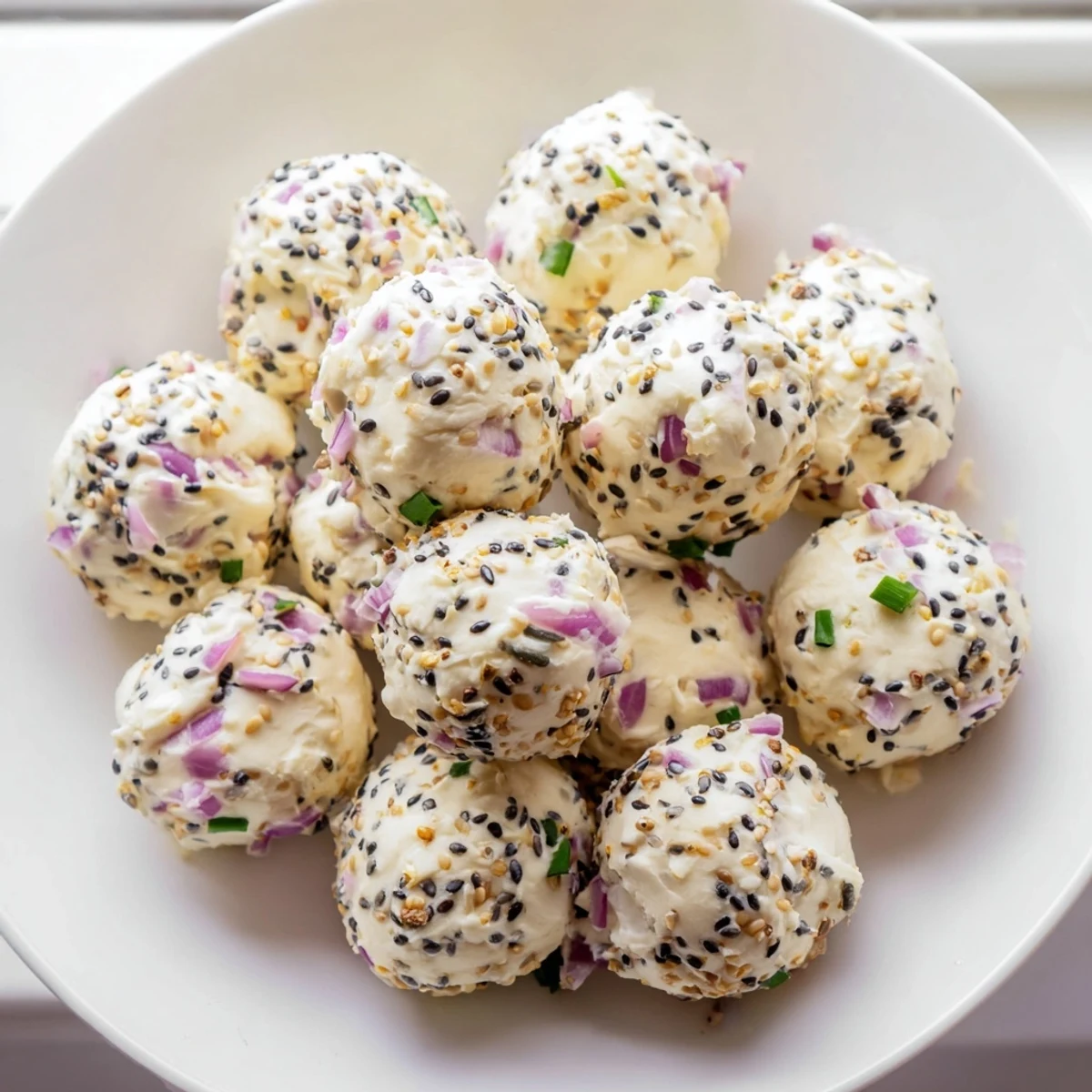 Chilled Everything Bagel Cottage Cheese Bites are plated with crisp cucumber slices and fresh red onion garnish.