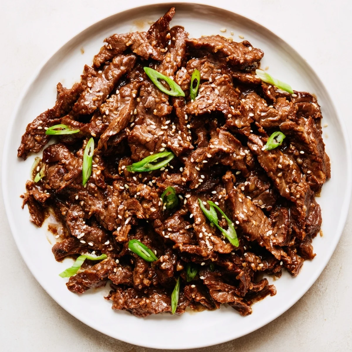Juicy shredded Crock Pot Korean Beef with a spicy-sweet glaze, garnished with green onions and served over jasmine rice.