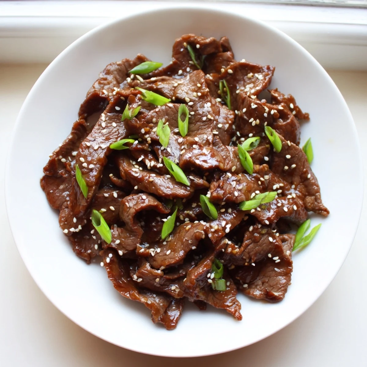 Fork-tender Ultimate Slow Cooker Mongolian Beef in thick glossy sauce, paired with steamed rice and scallions.