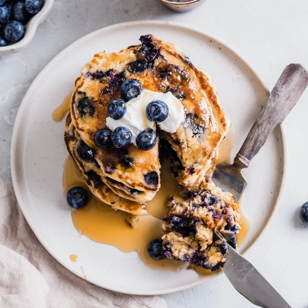 Served alongside coffee, these Fluffy Greek Yogurt Blueberry Pancakes offer a creamy, tangy, sweet breakfast delight.