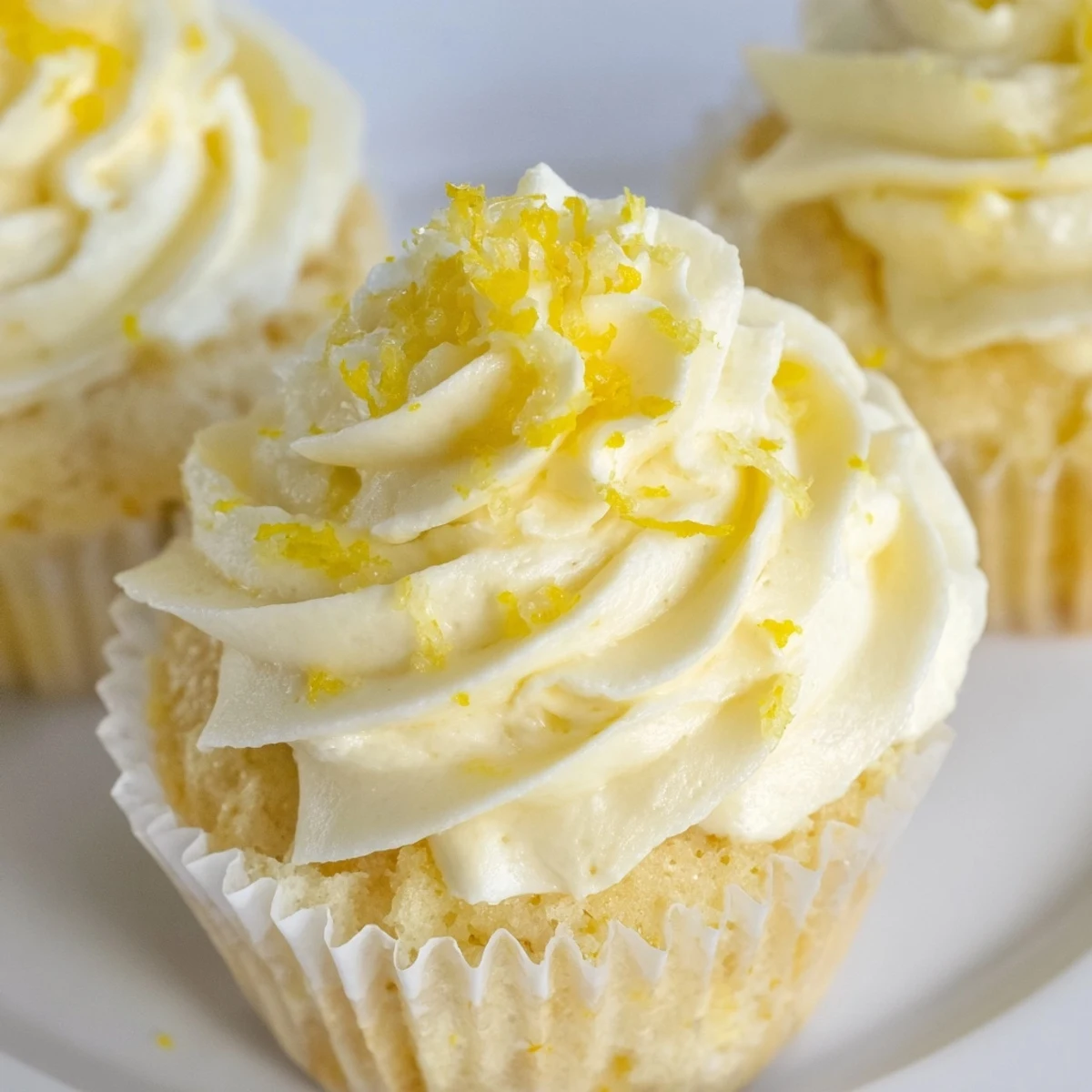 Freshly baked Limoncello Cupcakes topped with swirls of tangy lemon buttercream on a rustic wooden surface.