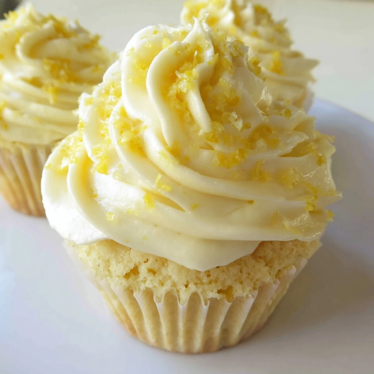 Twelve golden Limoncello Cupcakes arranged on a platter, perfect for a sunny summer dessert party.