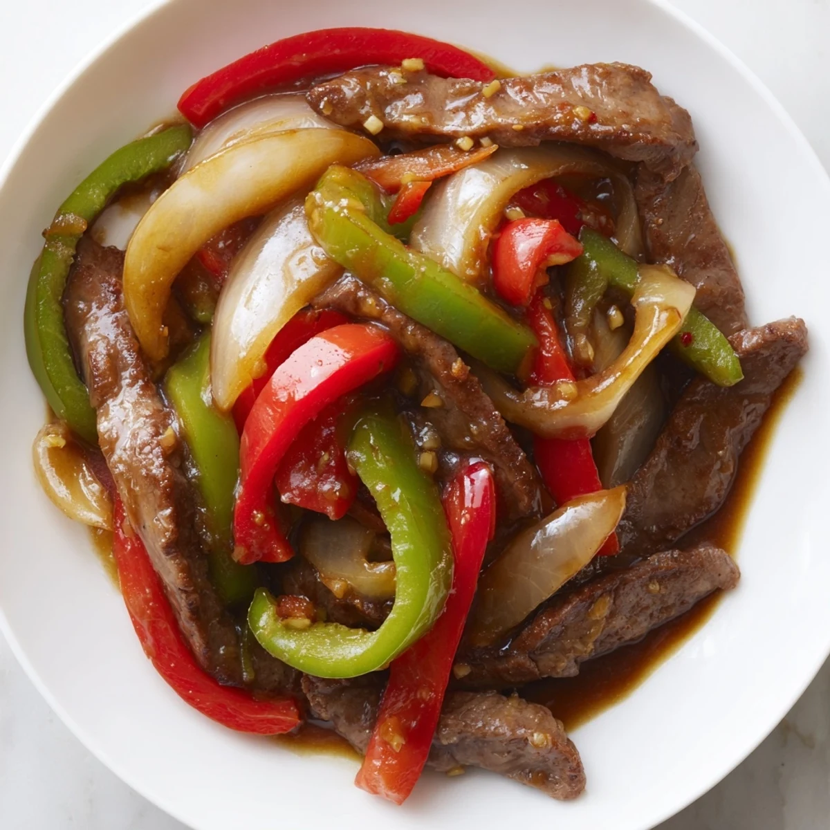 Sizzling Chinese Pepper Steak With Onions served hot over fluffy white rice with vibrant bell peppers.