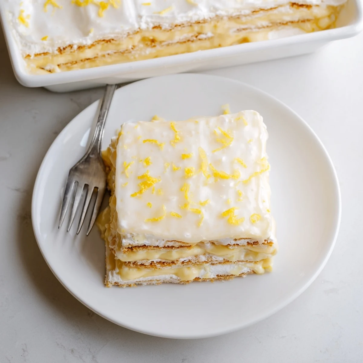 Delicate graham crackers soaked in lemon cream and silky glaze define this No Bake Lemon Eclair Cake dessert.