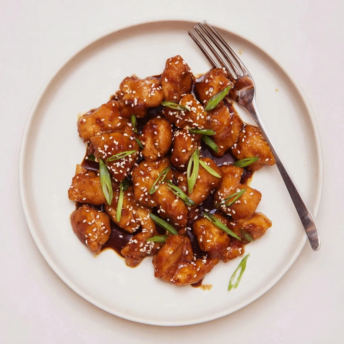 Tender crock pot huli huli chicken pieces garnished with sesame seeds and green onions