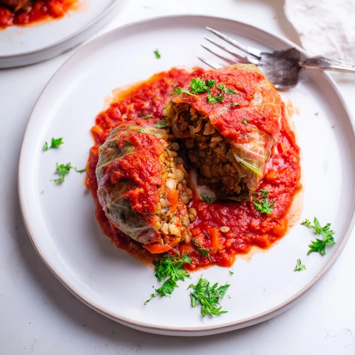 Golden vegan cabbage rolls nestled in rich tomato sauce with lentil rice filling