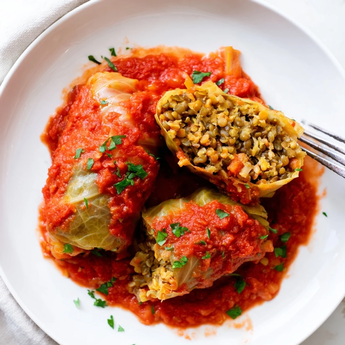 Steaming vegan cabbage rolls bathed in crushed tomato sauce showcasing plant-based filling