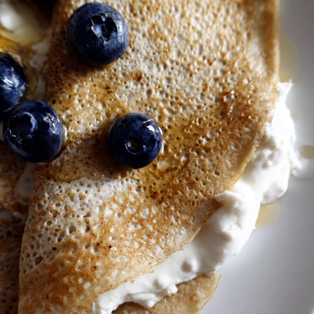 Thin wholesome healthy oatmeal crepes cooking in a skillet with golden brown edges showing