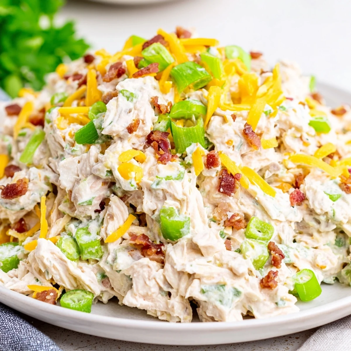 Chilled low carb jalapeno popper chicken salad bowl topped with bacon bits and fresh parsley garnish