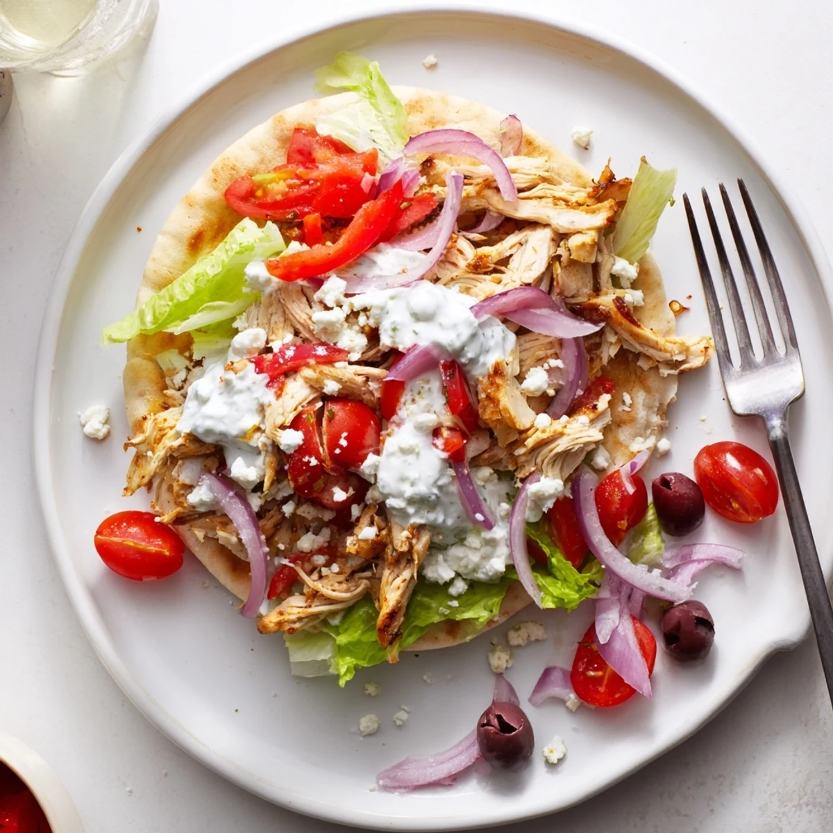 Mediterranean-style Greek chicken pitas overflowing with slow-cooked seasoned meat, feta cheese, olives, and homemade tzatziki