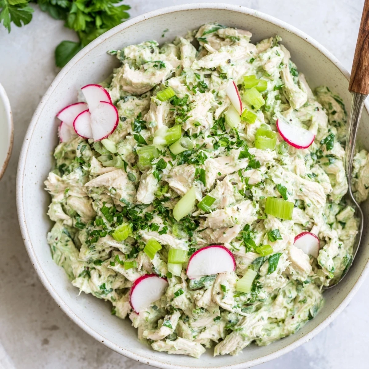 Golden crackers arranged beside a bowl of zesty Green Goddess Chicken Salad Dip topped with chives