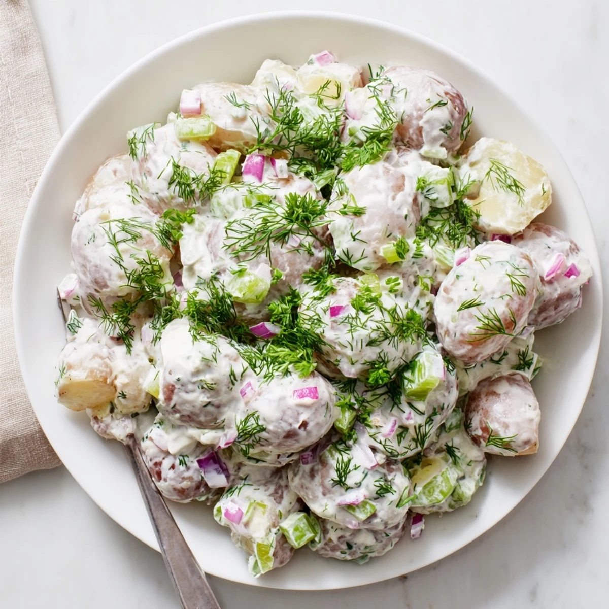 Light and tangy Greek yogurt potato salad with tender baby potatoes, crisp celery, and parsley garnish