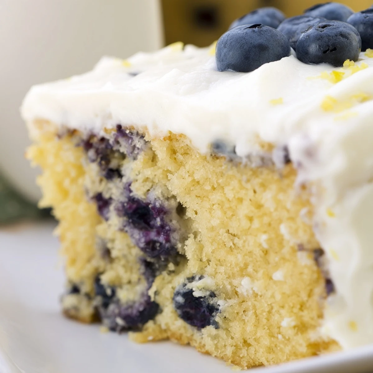 Two-layer lemon blueberry cake frosted with tangy cream cheese and lemon zest