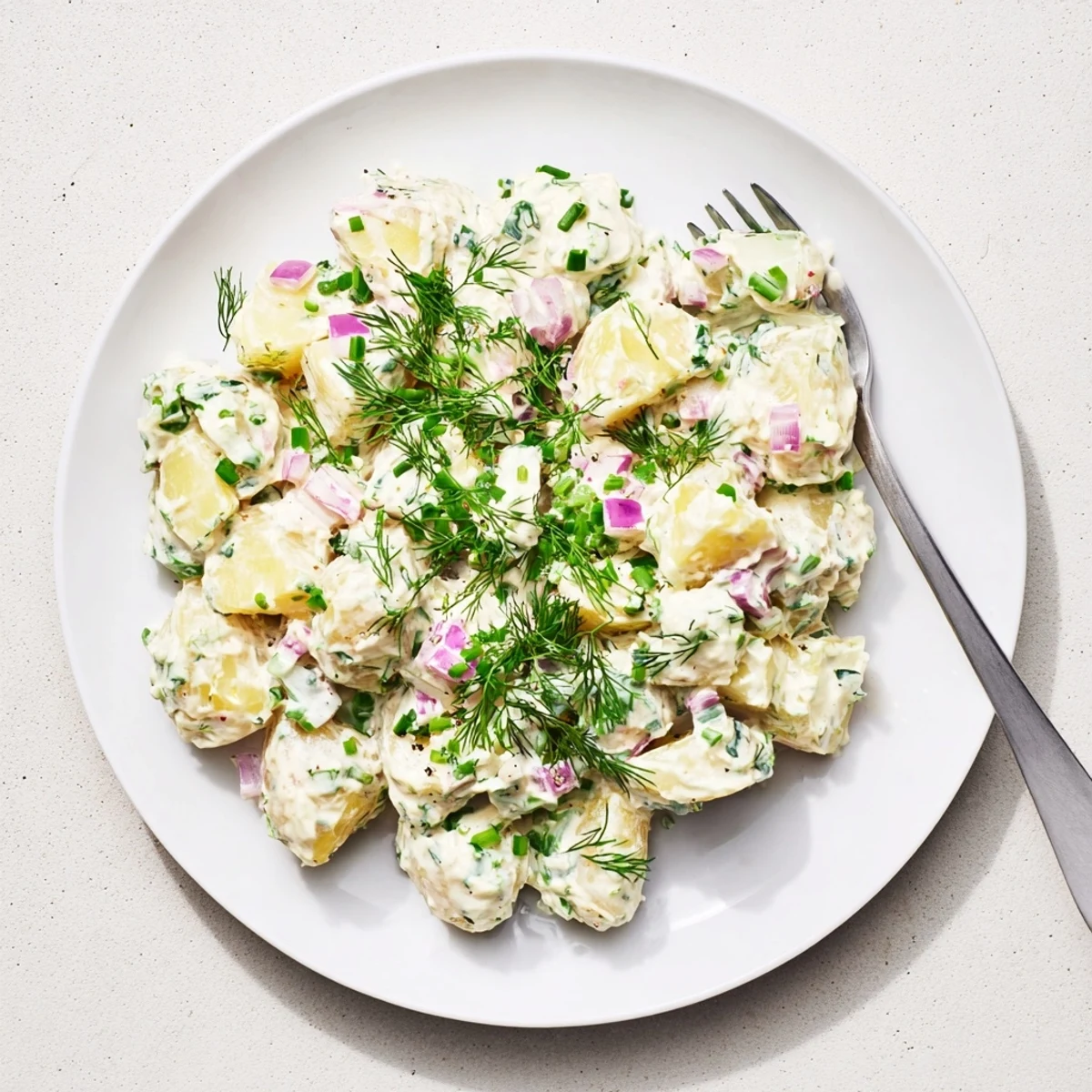 Light and tangy Greek yogurt potato salad topped with colorful diced vegetables and chopped dill