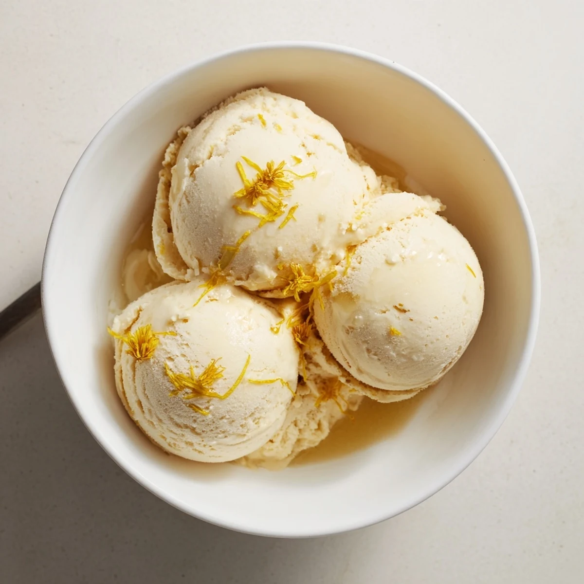 Velvety homemade dandelion honey ice cream garnished with fresh edible flowers for spring dessert.