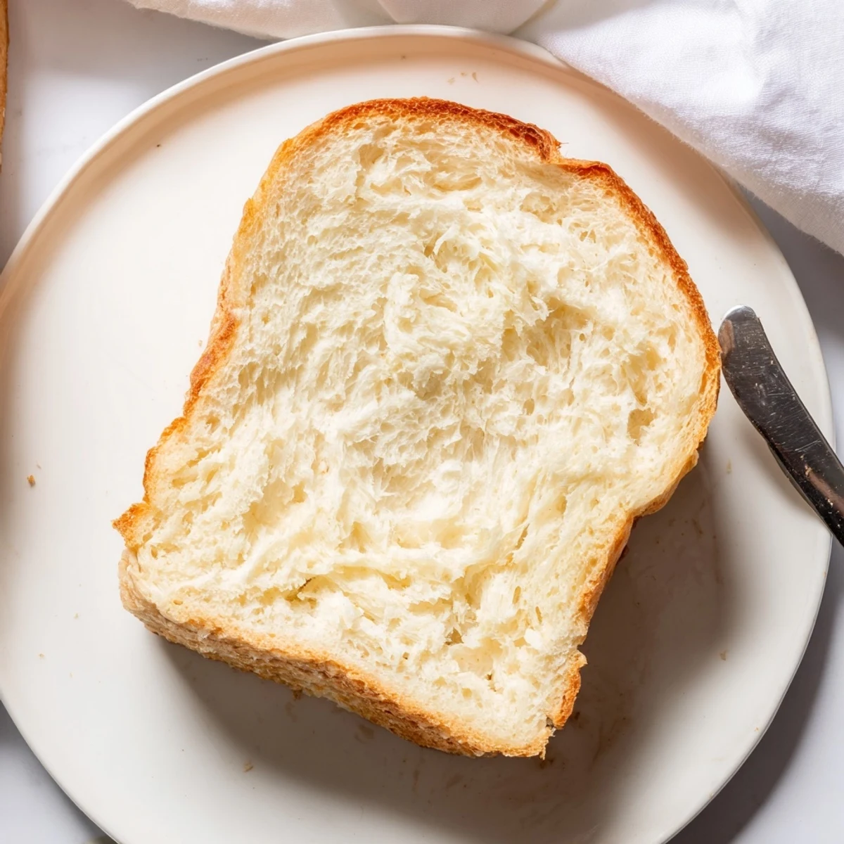 Golden brown homemade Amish white bread loaf with soft crumb, brushed with melted butter