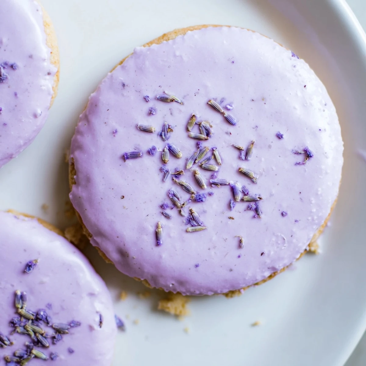 Soft lilac sugar cookies with delicate purple flecks arranged on a rustic white ceramic plate