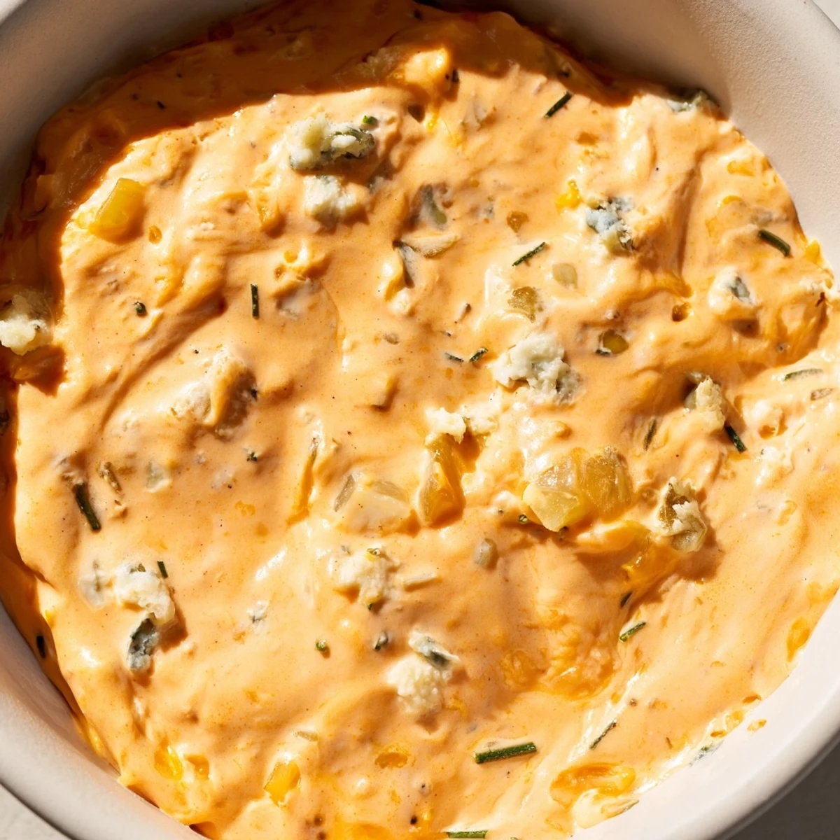 Creamy Buffalo Pickle Dip in a serving bowl surrounded by crunchy chips and fresh veggie sticks for party snacking