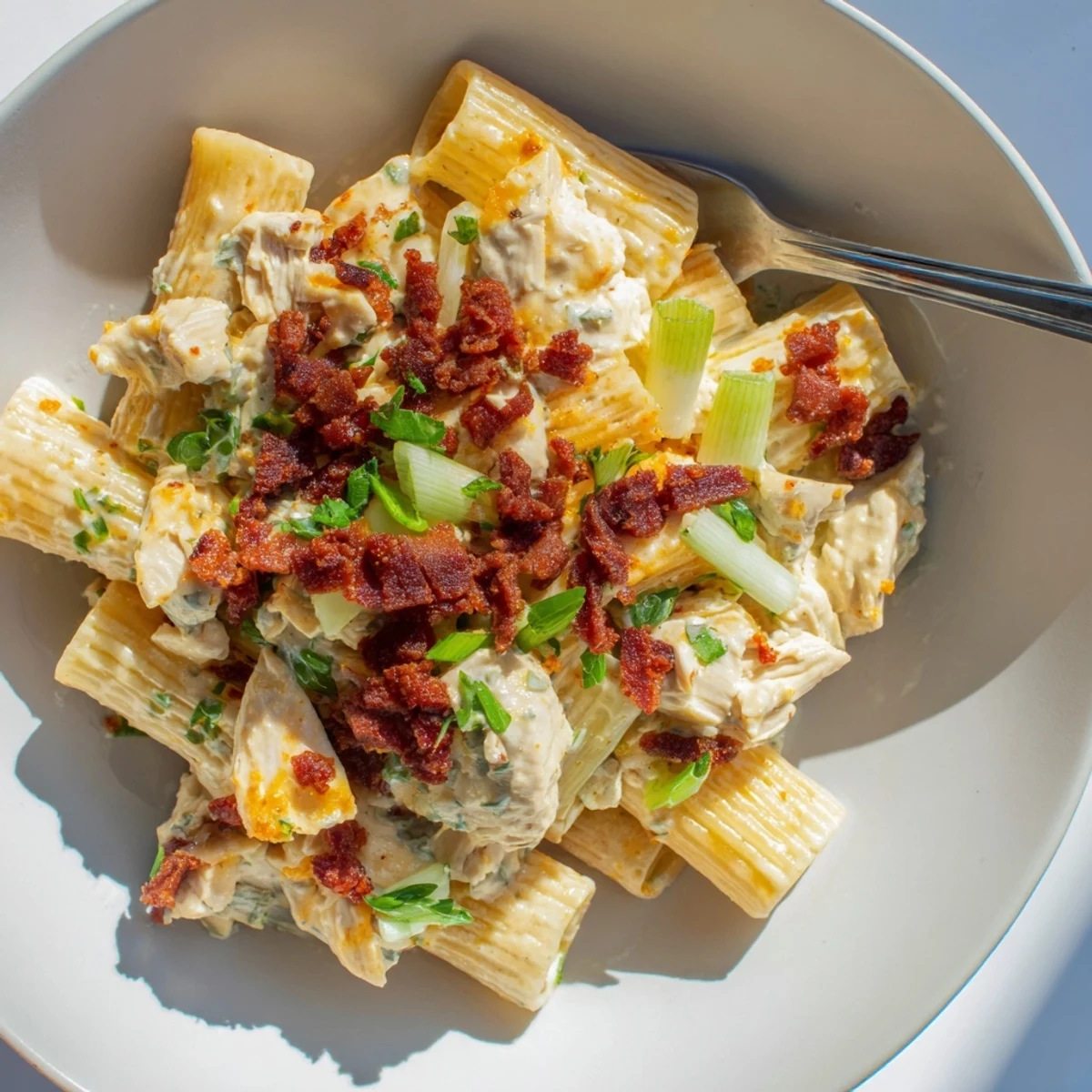 Creamy crack chicken pasta topped with crispy beef bacon and fresh green herbs