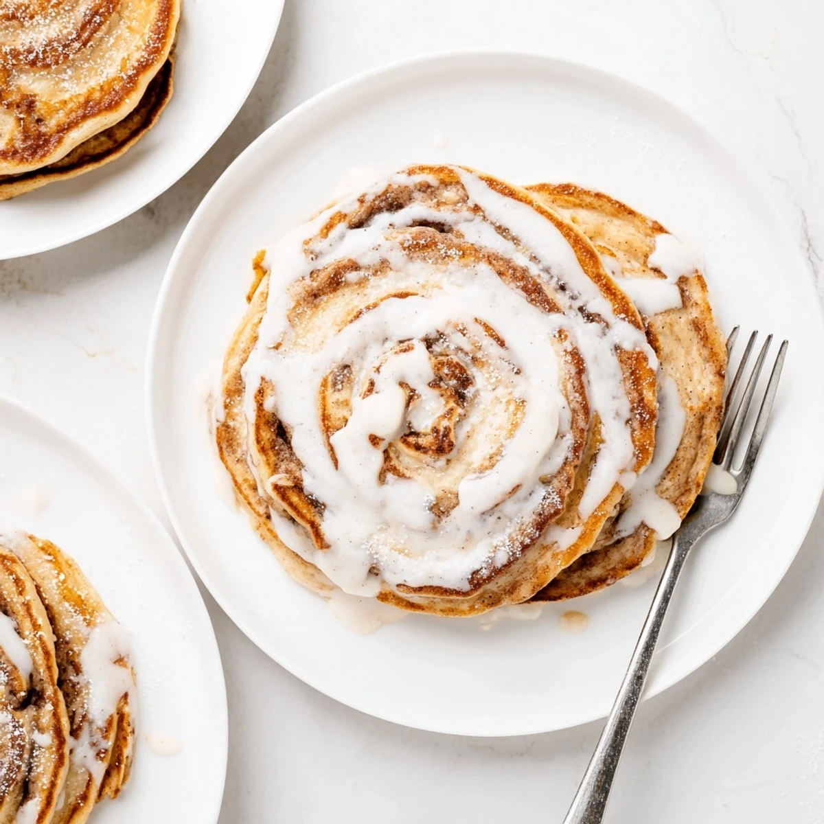 Golden cinnamon roll pancakes stacked high with creamy cream cheese icing drizzle