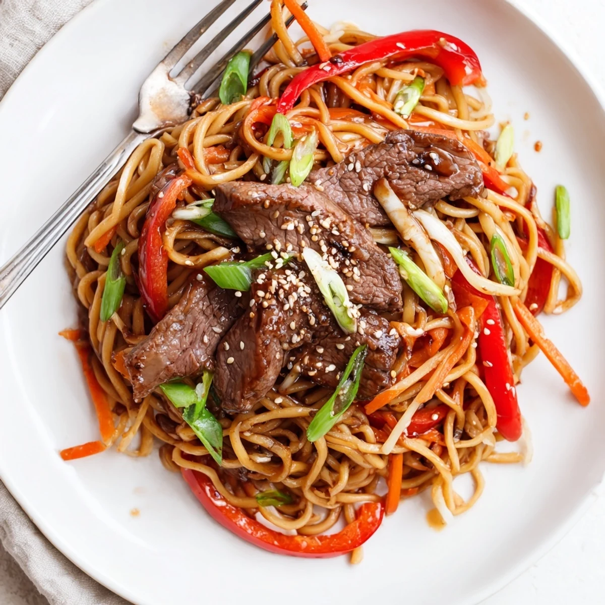 Sticky Beef Noodles glistening with glossy sauce, tender beef and sesame garnish