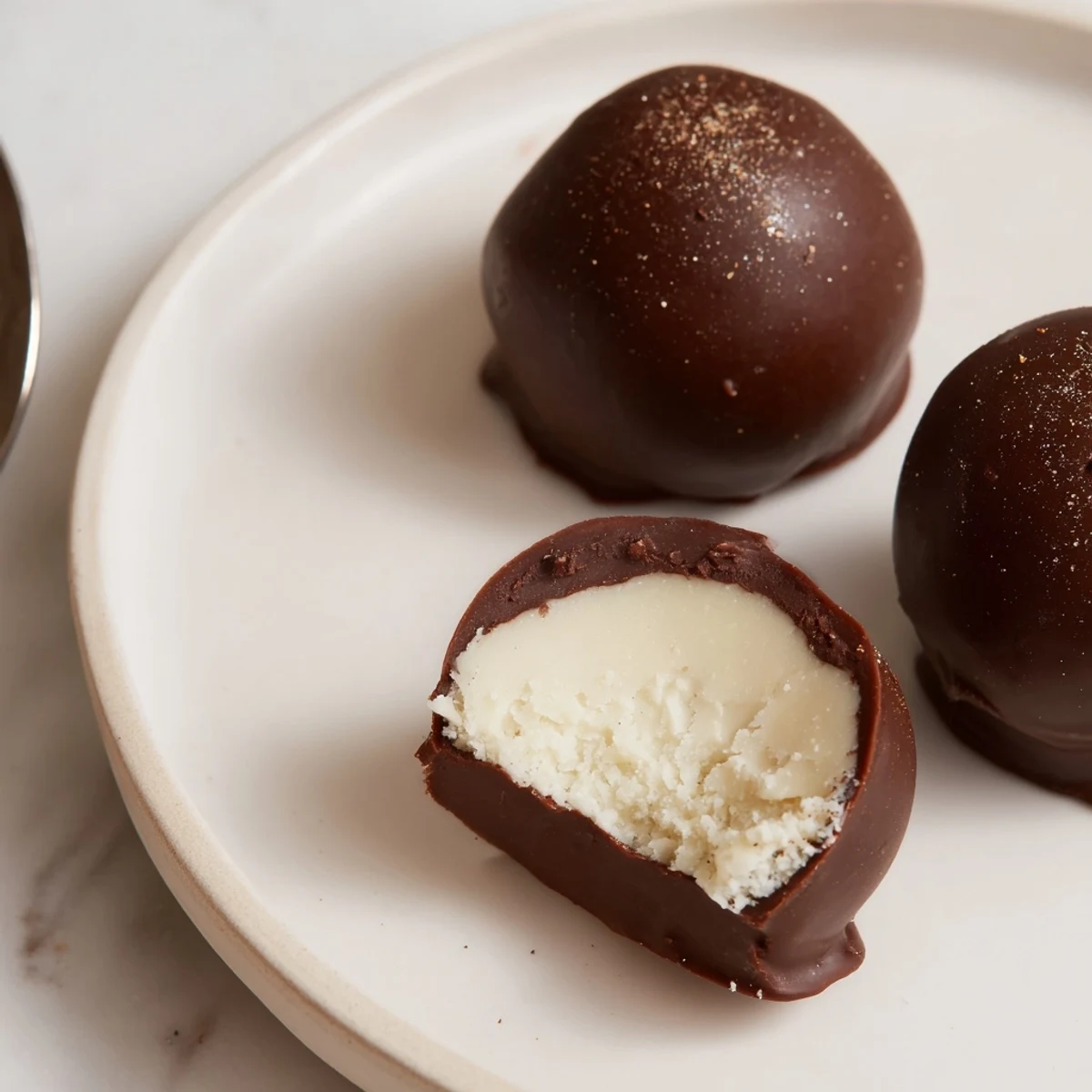 Dark Chocolate Eggnog Truffles on parchment, glossy shells dusted with warm nutmeg